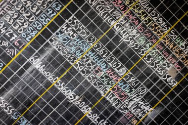 Okul tebeşiri tahtasında satırlarda yazılı numaralar var