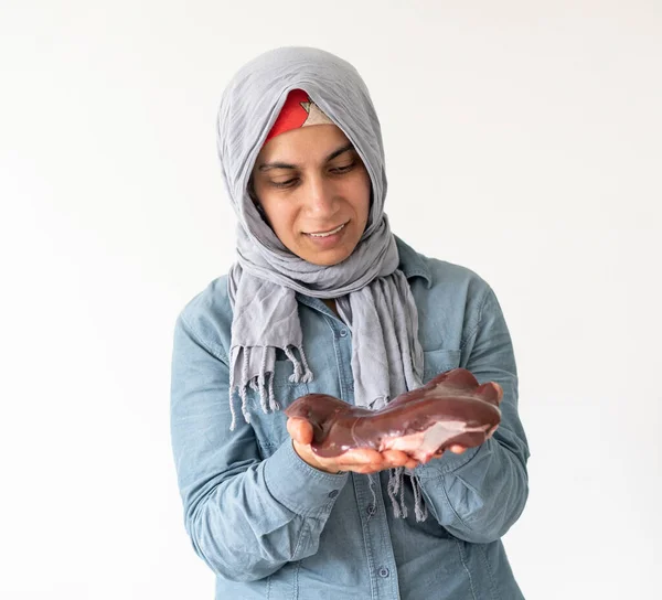 Czerwone surowe serce na tle w rękach muzułmanki — Zdjęcie stockowe