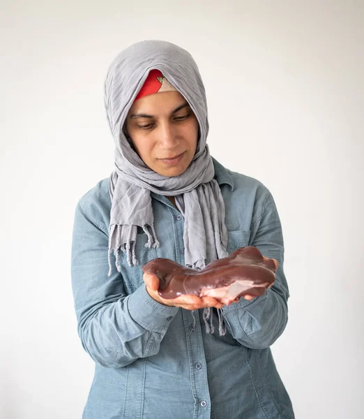 Czerwone surowe serce na tle w rękach muzułmanki — Zdjęcie stockowe