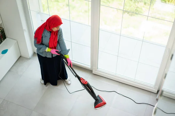 Ευτυχισμένη μουσουλμάνα γυναίκα καθαρισμού σύγχρονο σπίτι σαλόνι Εικόνα Αρχείου