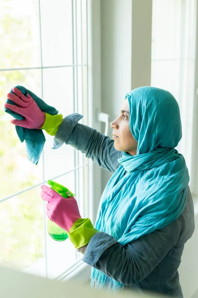 Щаслива мусульманка, яка прибирає сучасну вітальню — стокове фото