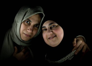 Siyah arka planda sarılan iki mutlu Müslüman kadın. Yüksek kalite fotoğraf