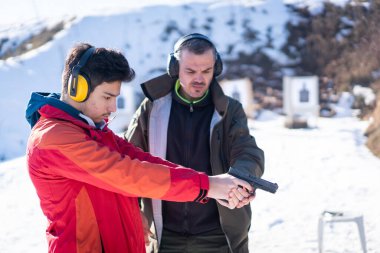 Antrenör, savaş eğitiminde genç insana tabancayla nişan almasında yardım ediyor. Yüksek kalite fotoğraf