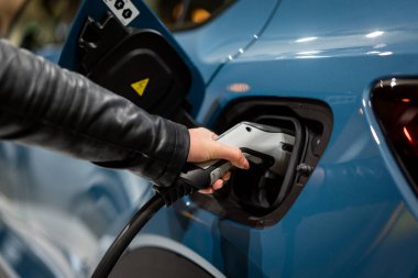 Aküyü şarj etmek için güç kaynağı elektrikli araca bağlanıyor. - Evet. EV yakıt Fişi hibrit arabaya takıldı. 