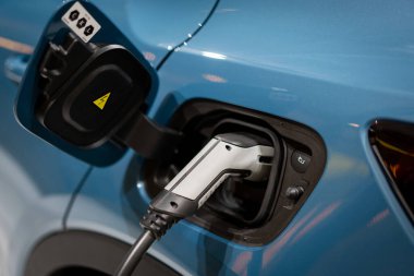 Aküyü şarj etmek için güç kaynağı elektrikli araca bağlanıyor. - Evet. EV yakıt Fişi hibrit arabaya takıldı. 