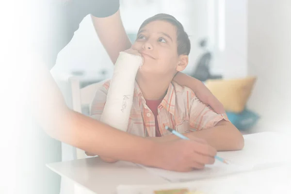 ジプサムで腕を骨折した少年は 宿題で兄の助けを借りている 高品質の写真 — ストック写真