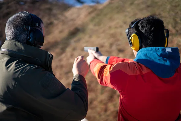 Trainer helping young person to aim with handgun at combat training. High quality photo