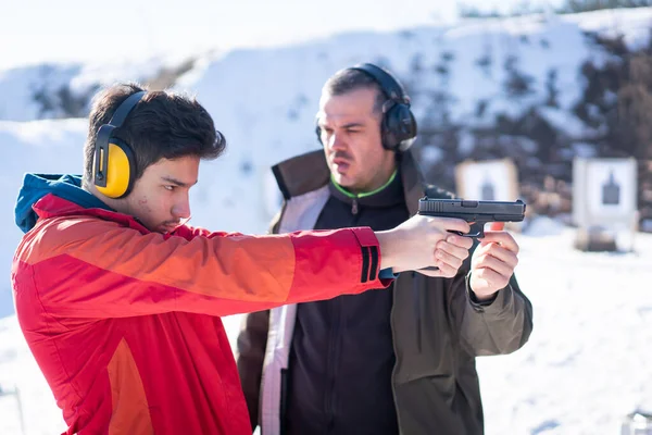 Trainer Hilft Jugendlichen Mit Handfeuerwaffen Auf Kampftraining Zielen Hochwertiges Foto lizenzfreie Stockfotos