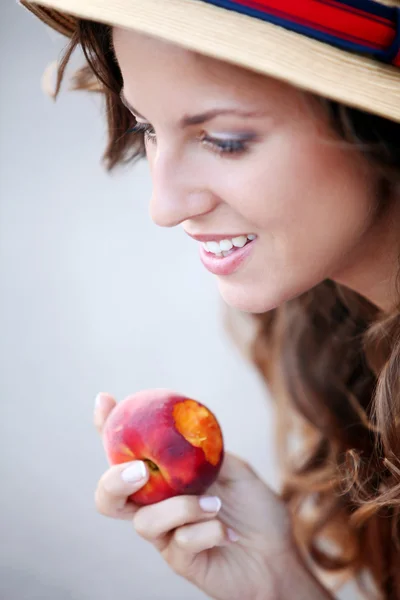 Young woman with fresh peach in her hand