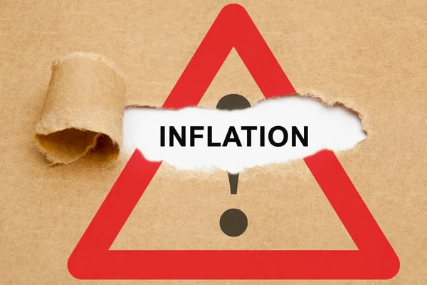 文字通货膨胀出现在注意路标上撕破的褐色纸片后面 关于提高通货膨胀率和接近金融危机的概念 图库图片