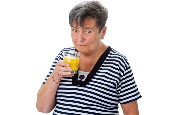 Starsza kobieta pije sok pomarańczowy — Zdjęcie stockowe