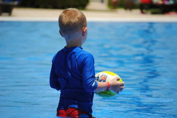 Menino relaxante na piscina com bola Fotografias De Stock Royalty-Free