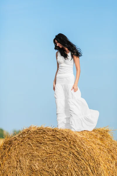 Young woman standing on a hay bale — Stock Photo, Image