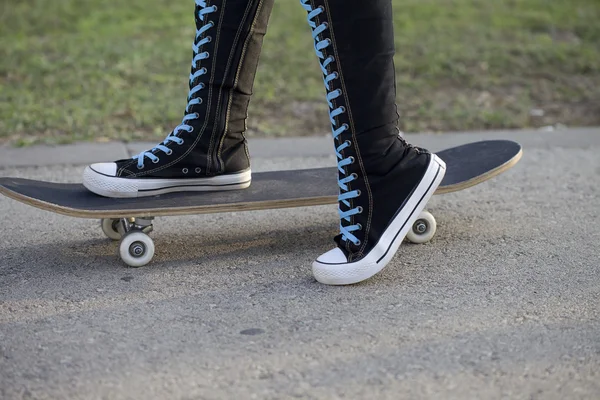 Frau mit Skateboard in Turnschuhen mit hohen Knien. — Stockfoto