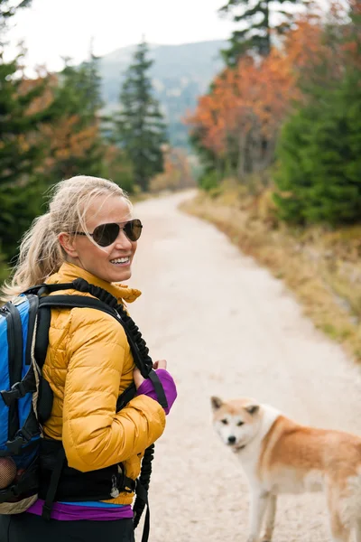 Mulher caminhando em montanhas com cão akita — Fotografia de Stock