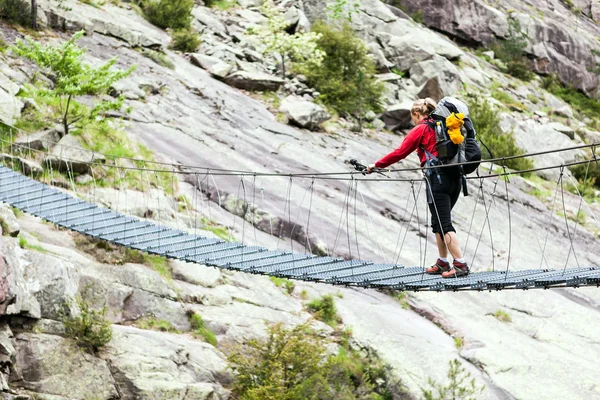 Senderismo de mujer con mochila cruzando puente — Foto de Stock