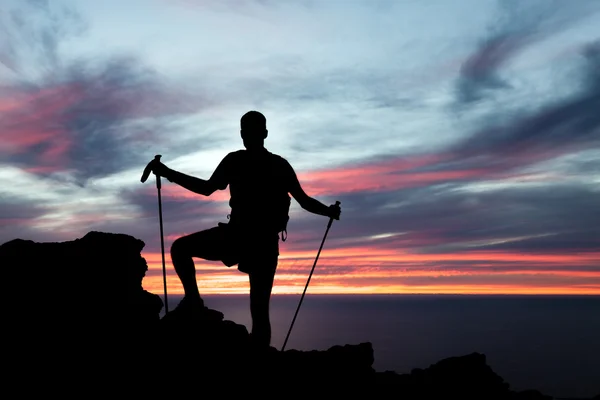 男子徒步旅行在高山、 海洋和夕阳剪影 — 图库照片