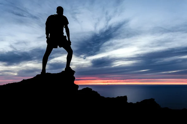Uomo silhouette escursionistica in montagna, oceano e tramonto — Foto Stock