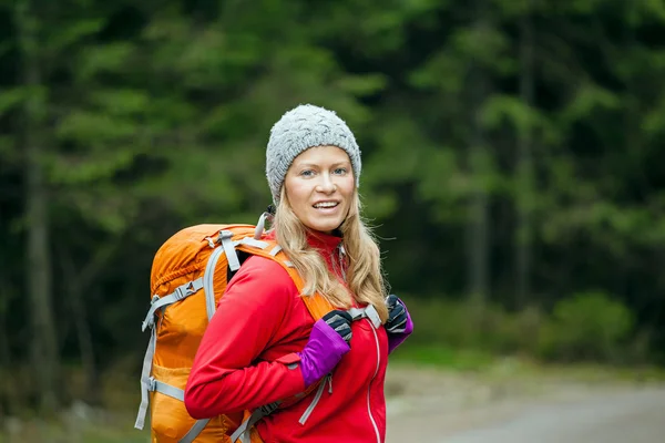 Woman hiker with backpack hiking in forest