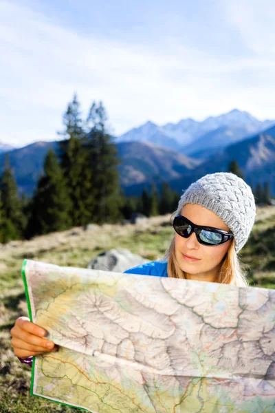 Woman hiker reading map in mountains