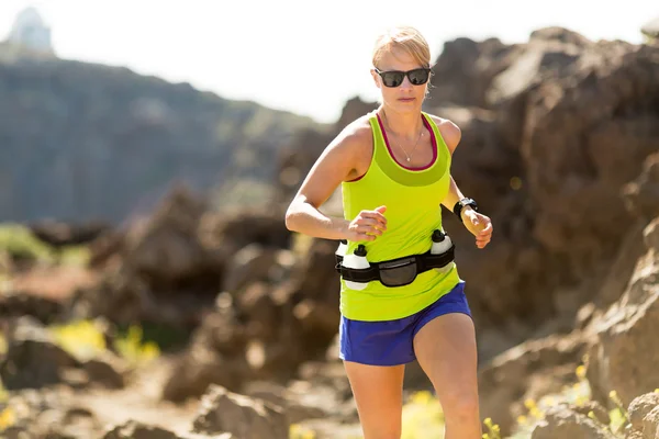 Mujer joven corriendo en las montañas en el soleado día de verano — Foto de Stock