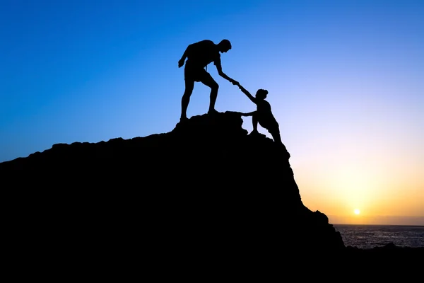 Man and woman help silhouette in mountains — Stock Photo, Image