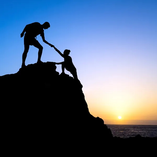 Man and woman help silhouette in mountains — Stock Photo, Image