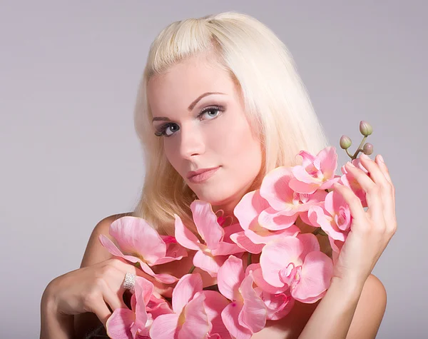 Piękna twarz młodej kobiety z różowy storczyk na tle — Zdjęcie stockowe