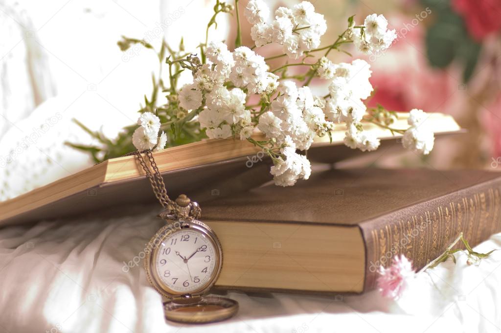 Vintage pocket watch near spectacles on old book