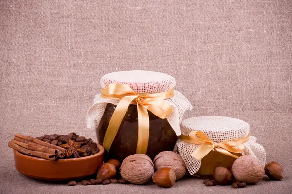 Tasty jam, cupcakes, clay pot and nuts on background — Stock Photo, Image