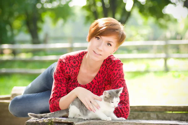 Vacker ung flicka i parken med en katt — Stockfoto