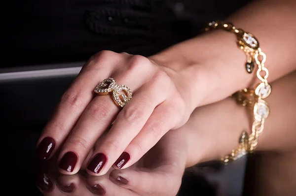 Mão com um anel e pulseira em um fundo preto — Fotografia de Stock