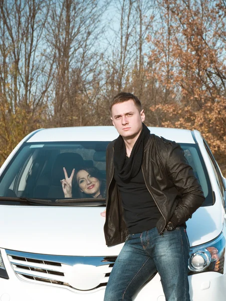 Vonzó fiatal férfi állandó autóval. A kocsiban ült barátnője — Stock Fotó
