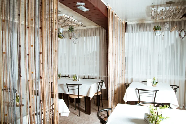 Interior of modern restaurant with the covered tables, wooden furniture — Stock Photo, Image