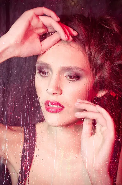 Girl watching through the rainy window — Stock Photo, Image