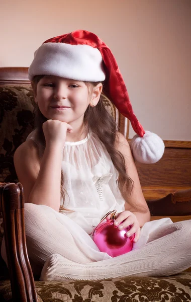 Красивая маленькая девочка в белом платье с украшением елки — стоковое фото