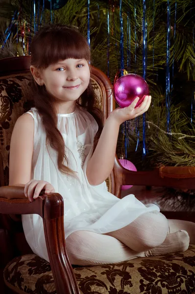 Mooi meisje in witte jurk met kerstboom decoratie — Stockfoto