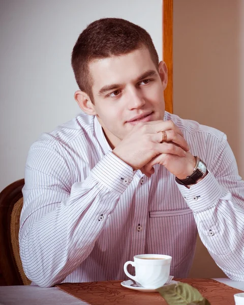 Młody człowiek z filiżanką kawy w kawiarni — Zdjęcie stockowe