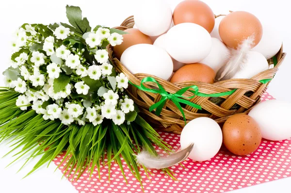 Cesta com ovos de Páscoa e flores de primavera no fundo branco — Fotografia de Stock