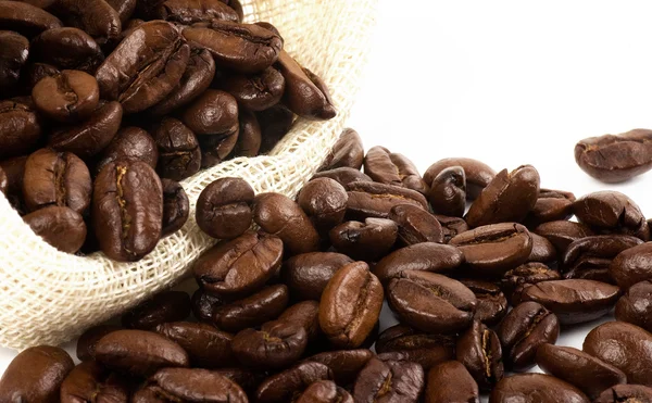 Grãos de café em saco de lona no fundo branco — Fotografia de Stock