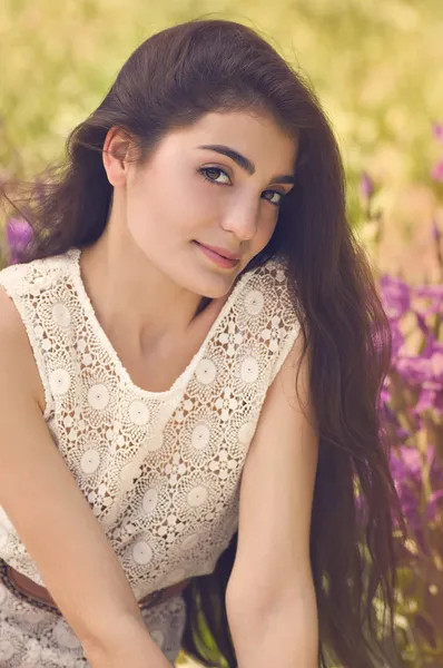 Menina bonita em vestido de verão branco de pé no jardim, sorrindo . — Fotografia de Stock