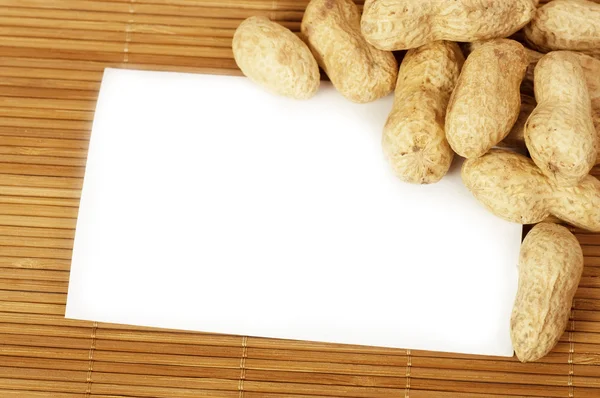 Tasty nuts with white blank paper — Stock Photo, Image