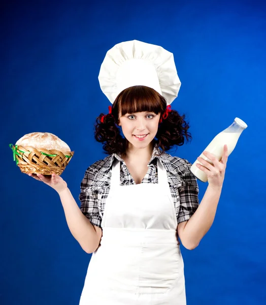 Sonriente mujer cocinera feliz sostiene una leche y pan — Foto de Stock