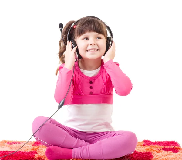 Güzel küçük bir kız kulaklık ile müzik dinlemek olduğunu — Stok fotoğraf