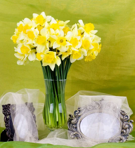 在一个玻璃花瓶和背景上的帧中的美丽春天的花朵 — 图库照片