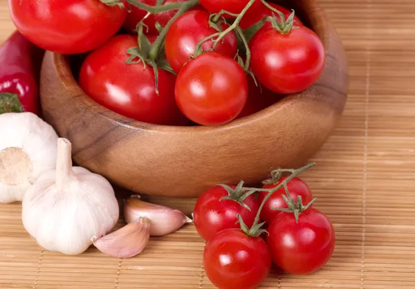 Verse tomaten met knoflook in houten kom — Stockfoto