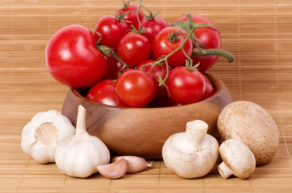 Fresh tomatoes with garlic in wooden bowl — Stock Photo, Image