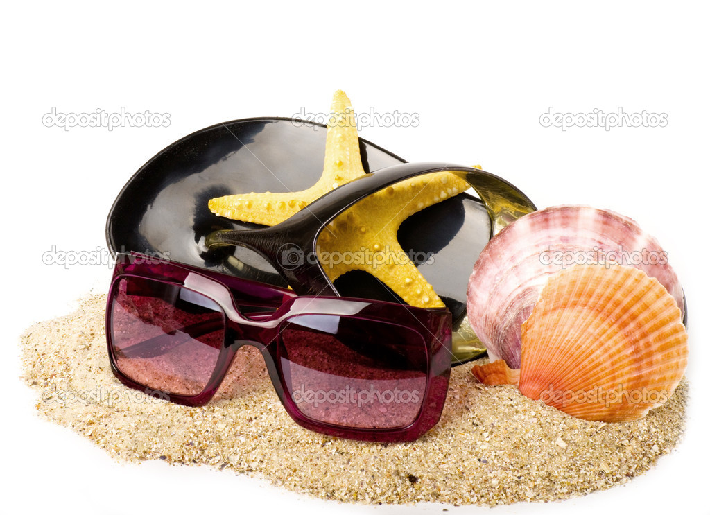 Beautiful exotic shell, shoe and glasses on sand