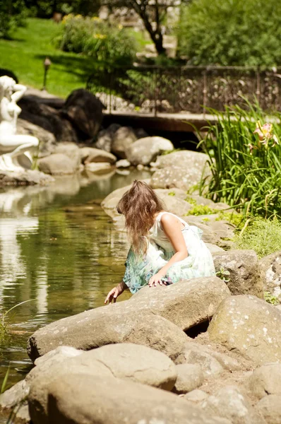 Meisje zit op steen in de buurt van Lente — Stockfoto