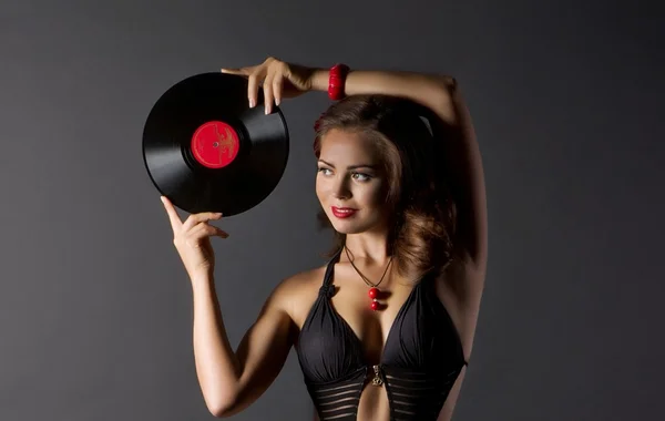 Sexy mujer joven en estilo retro con placa de vinilo sobre fondo negro . —  Fotos de Stock
